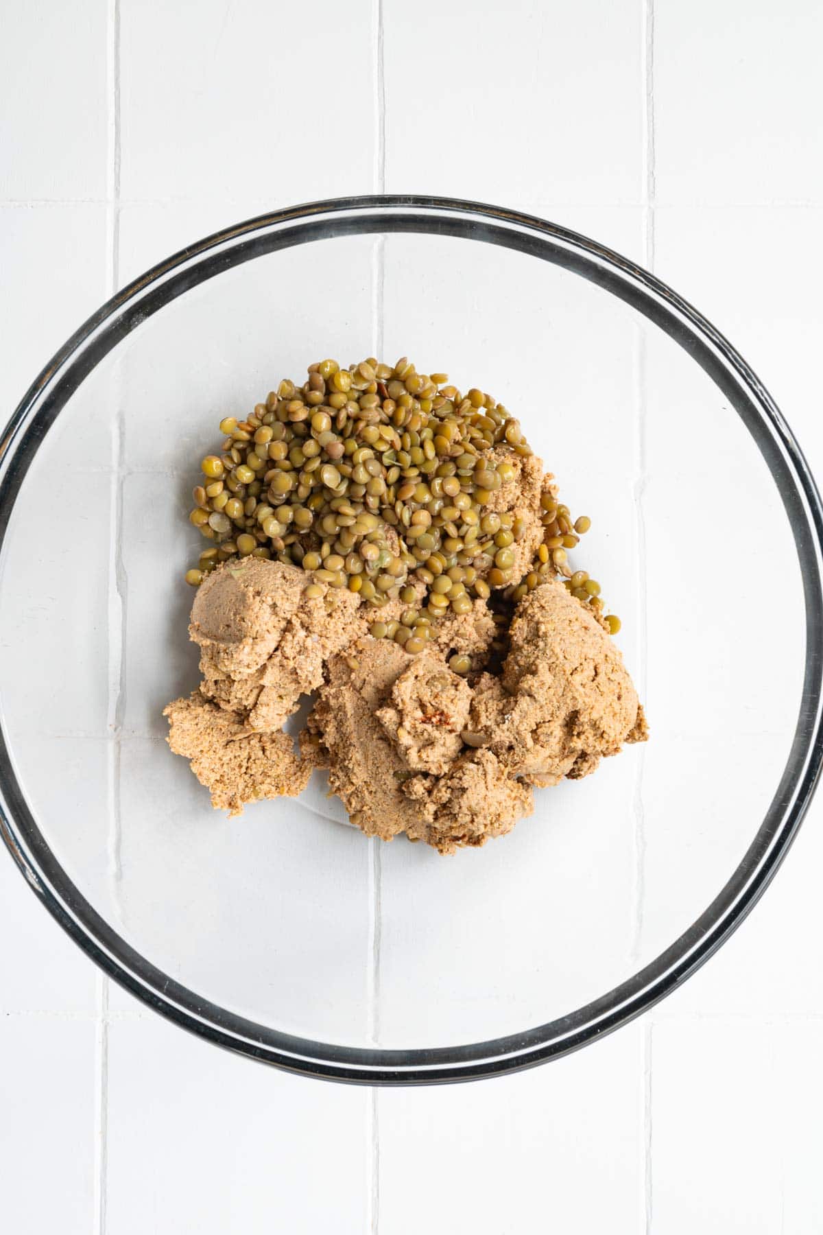 Tofu lentil mixture with cooked green lentils in a glass bowl.