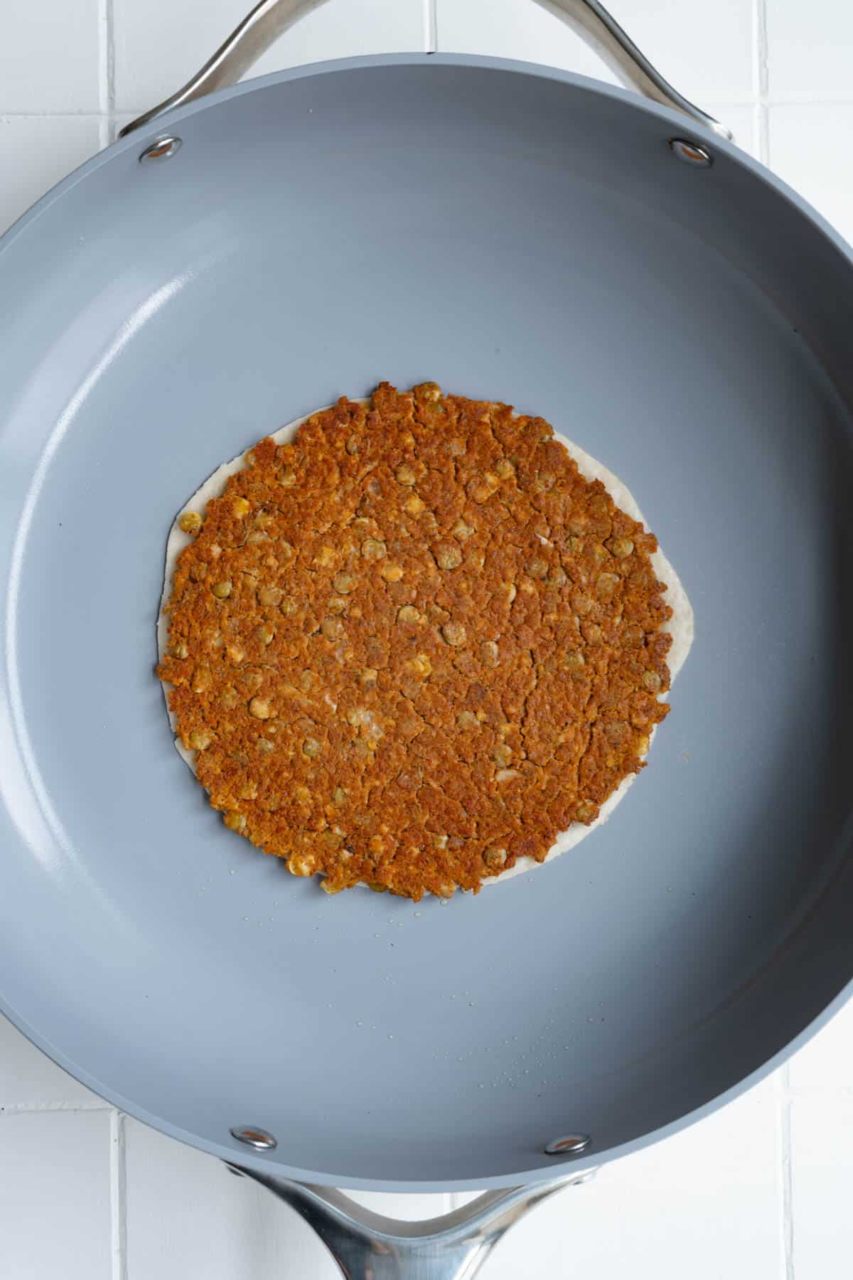 Vegan smash burger taco cooking in a nonstick pan.