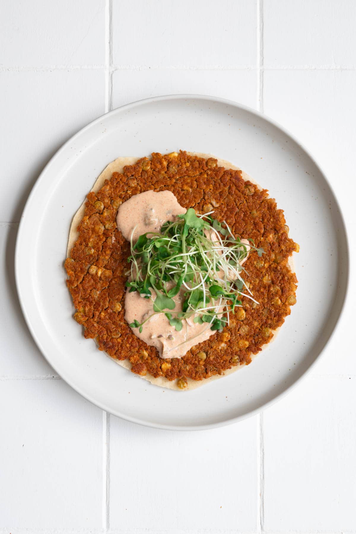 One vegan smash burger tacos with burger sauce on a white plate.