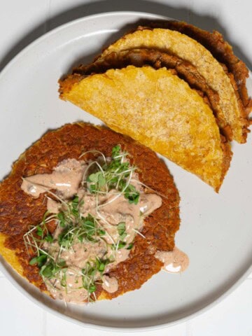 Vegan smash burger tacos with burger sauce on a white plate.