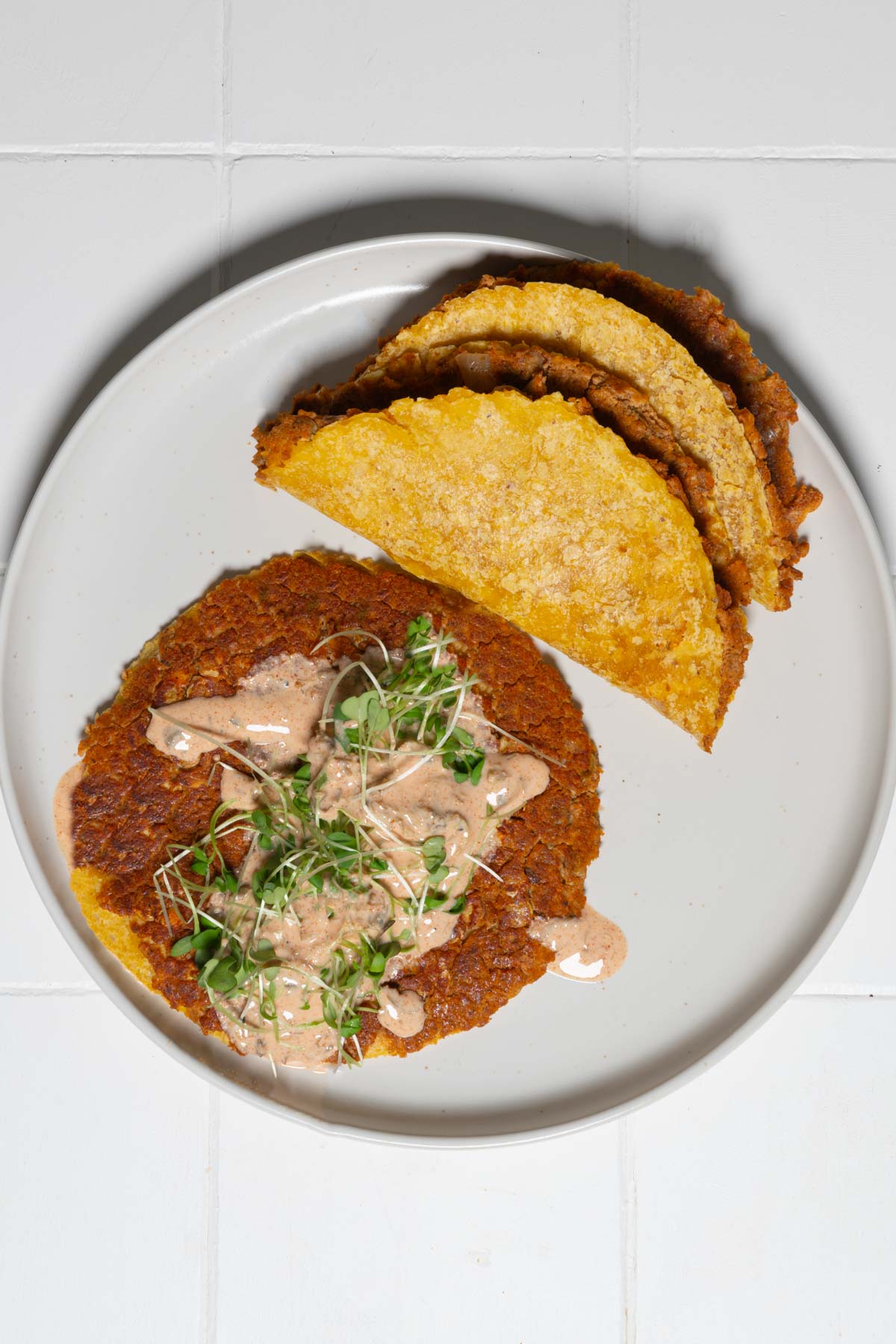 Vegan smash burger tacos with burger sauce on a white plate.