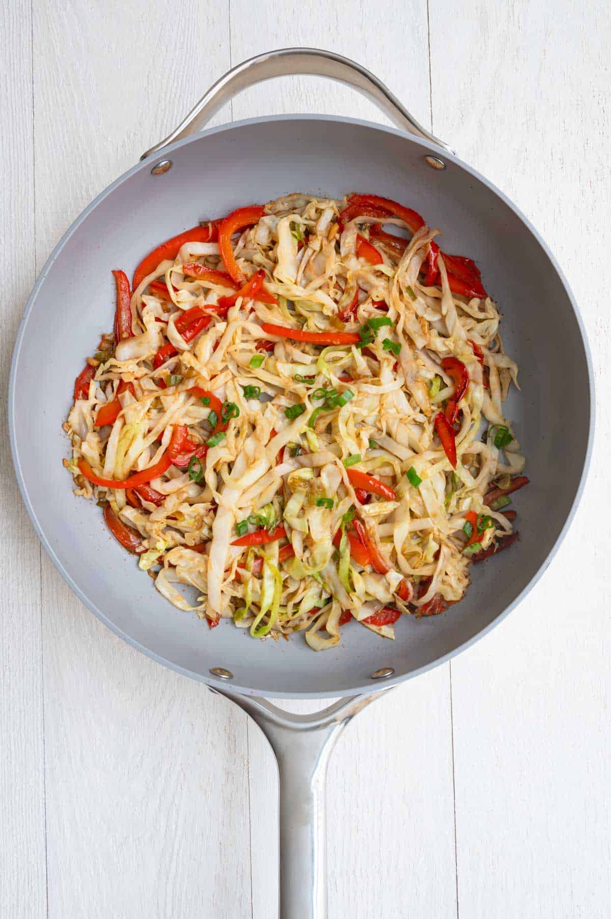 Cabbage stir-fry cooking in a skillet.