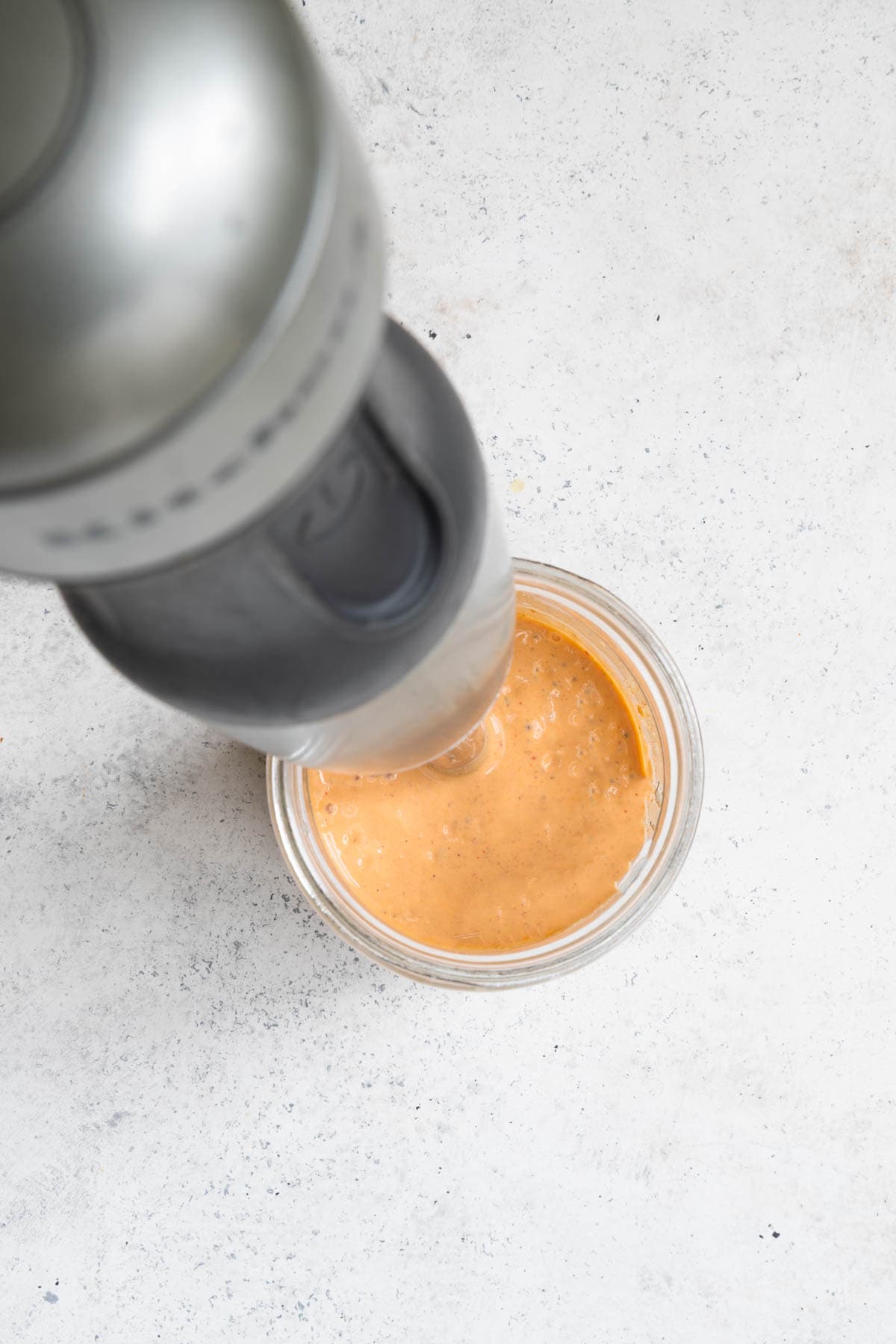 Chipotle yogurt dressing in a glass jar with an immersion blender.