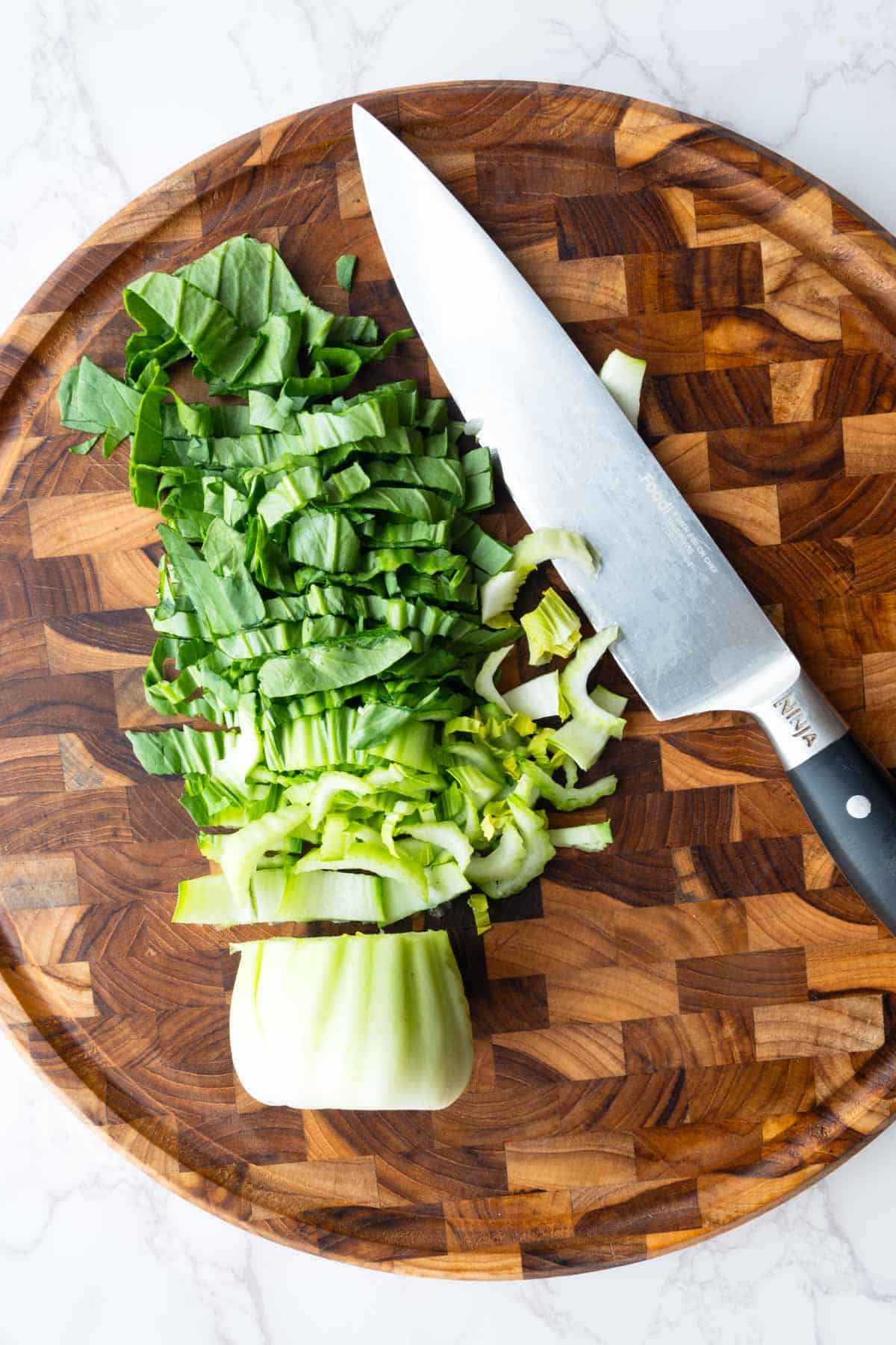 Chopped bok choy on a wooden cutting board.