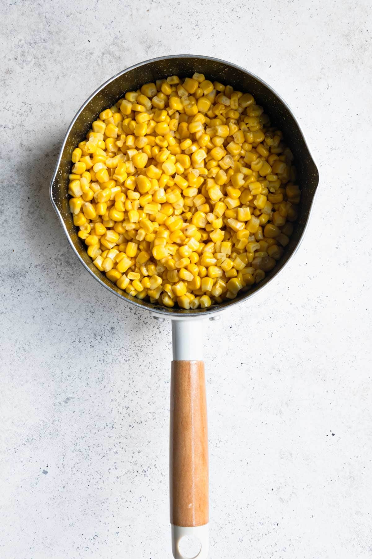 Heated corn in a white saucepan.