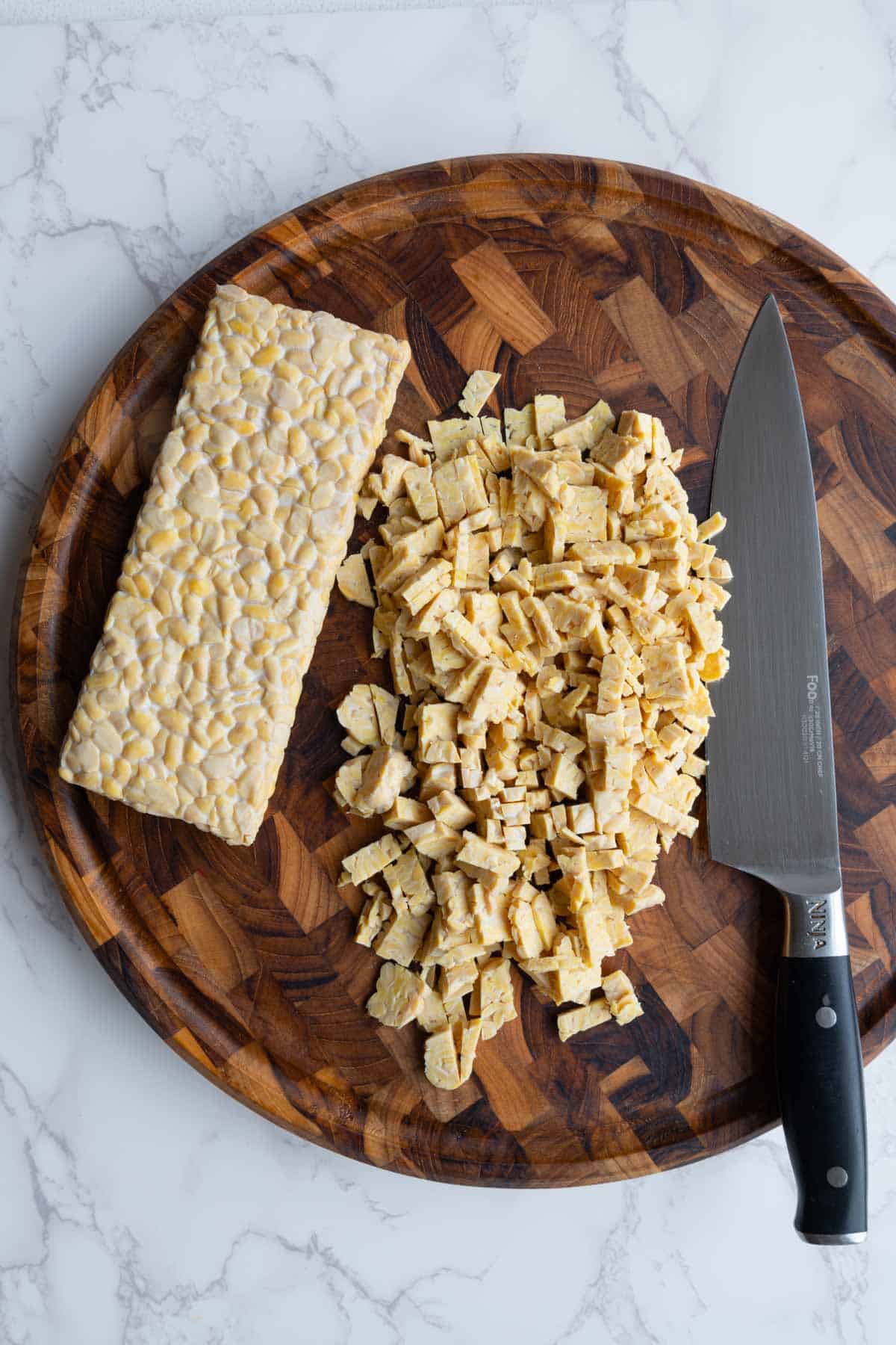 Chopped tempeh on a wooden cutting board.