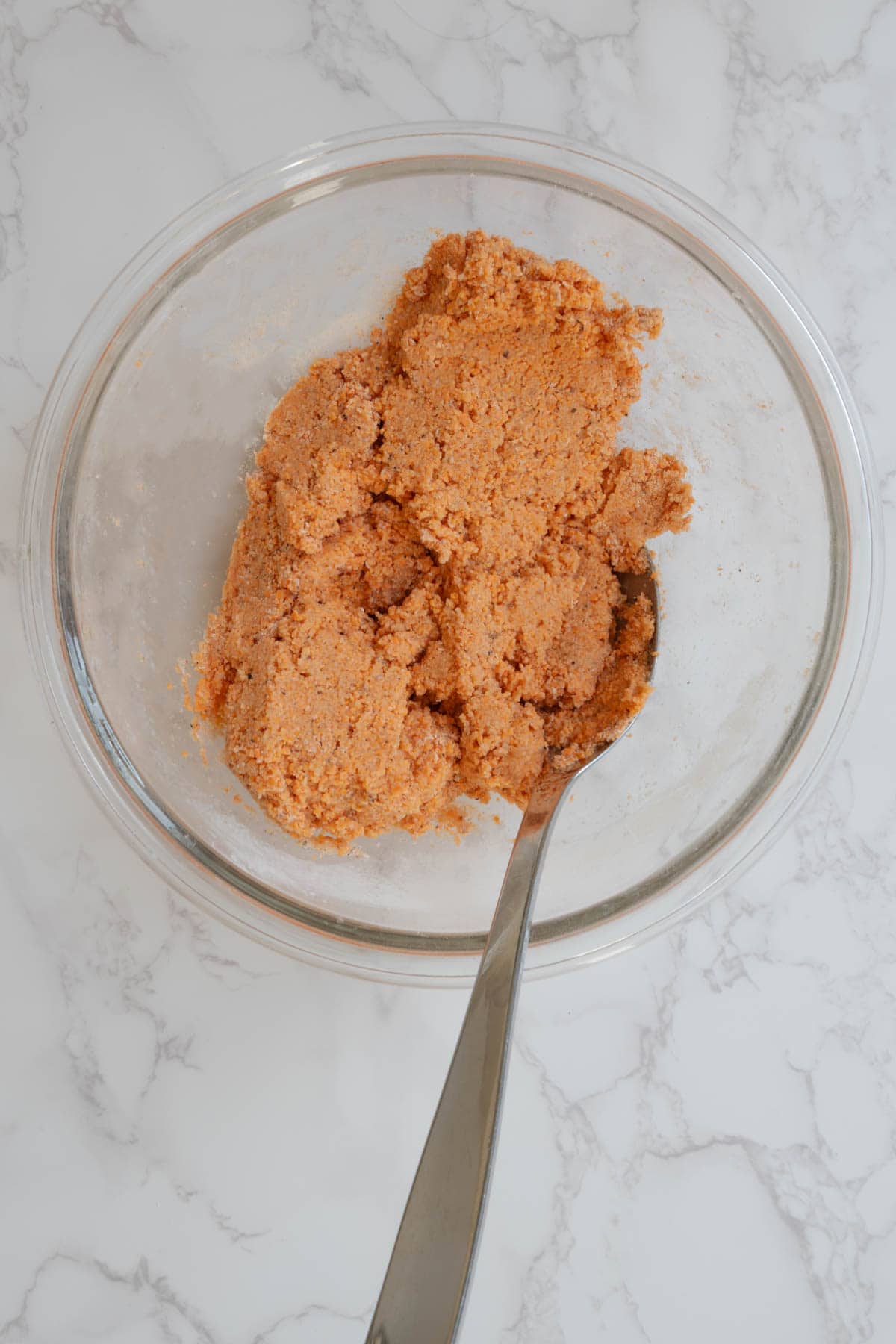 Orange dough and spoon in a bowl.