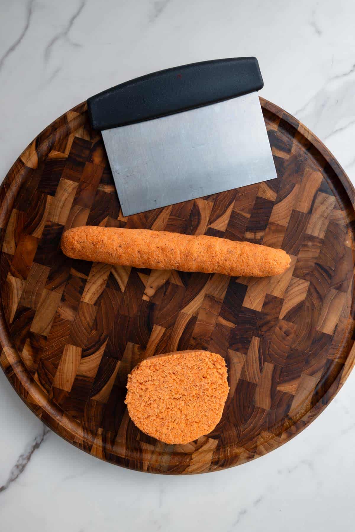 Orange dough sliced on a wooden cutting board.