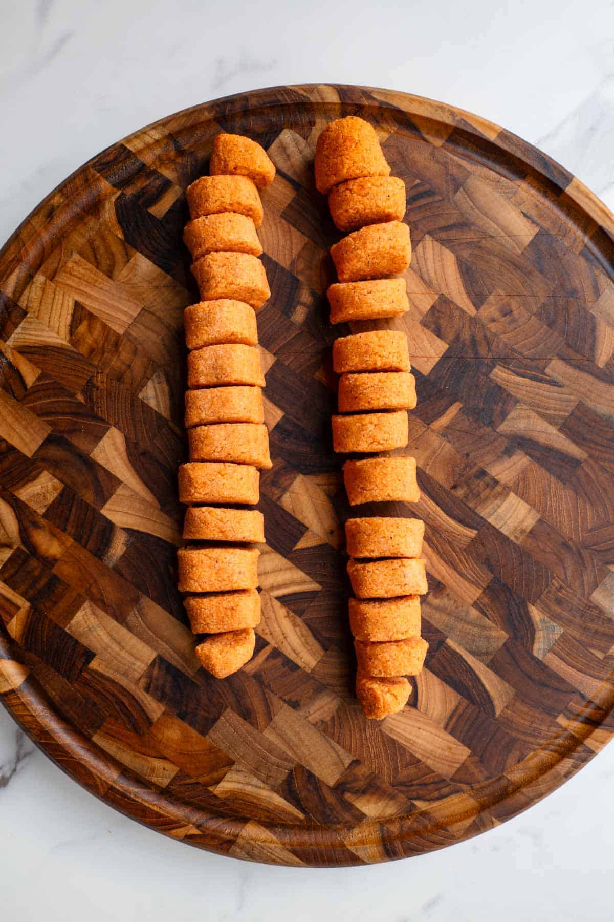Sliced gnocchi on a wooden cutting board.