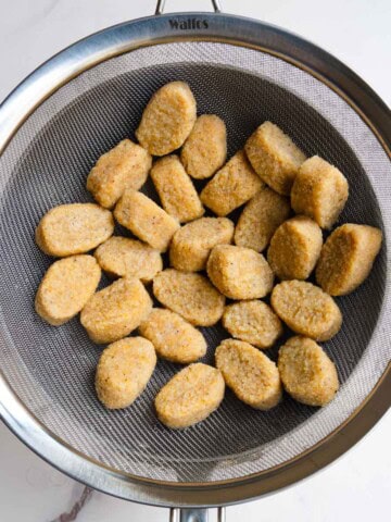 Homemade gnocchi in a fine mesh sieve.