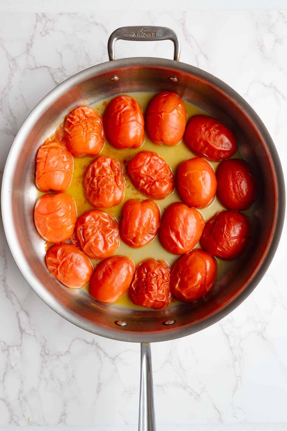 Cooked halved tomatoes in a large skillet.