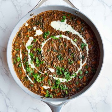 Iron-rich easy dal recipe in a skillet toped with nondairy cream and fresh cilantro.