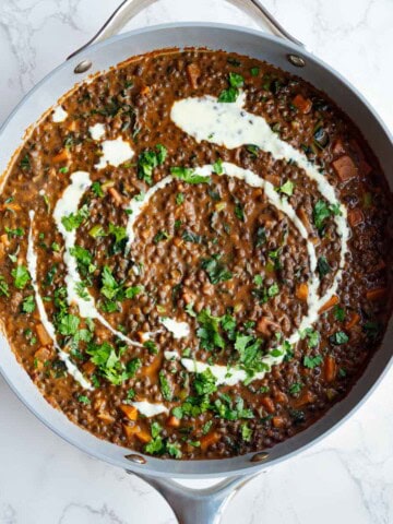 Iron-rich easy dal recipe in a skillet toped with nondairy cream and fresh cilantro.