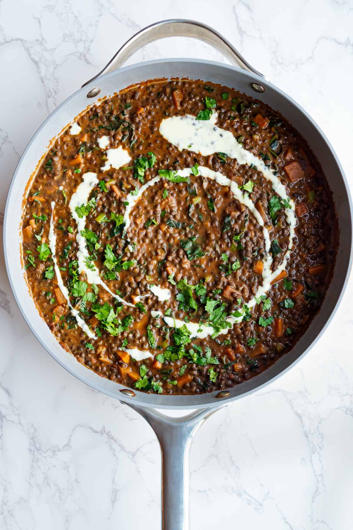 Iron-rich easy dal recipe in a skillet toped with nondairy cream and fresh cilantro.