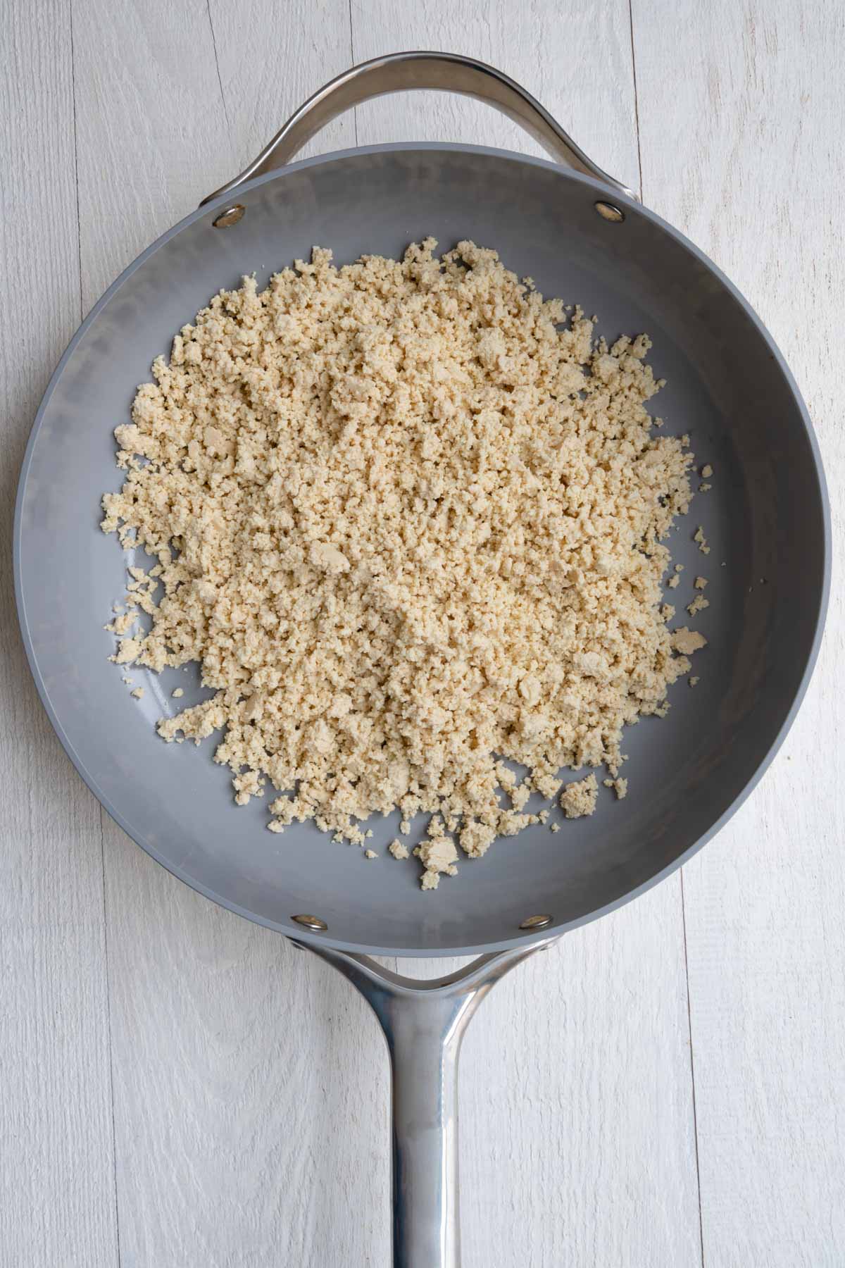 Tofu crumbled into a skillet.