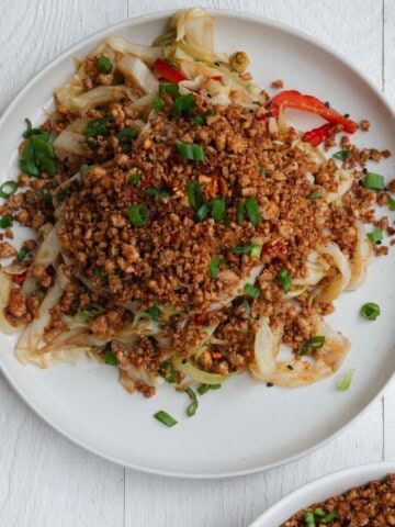 Pan-fried tofu crumbles in a bowl and sprinkled on a cabbage stir fry.