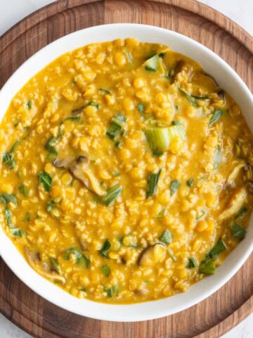 Savory protein porridge with oats and red lentils in a white bowl on a wooden board.