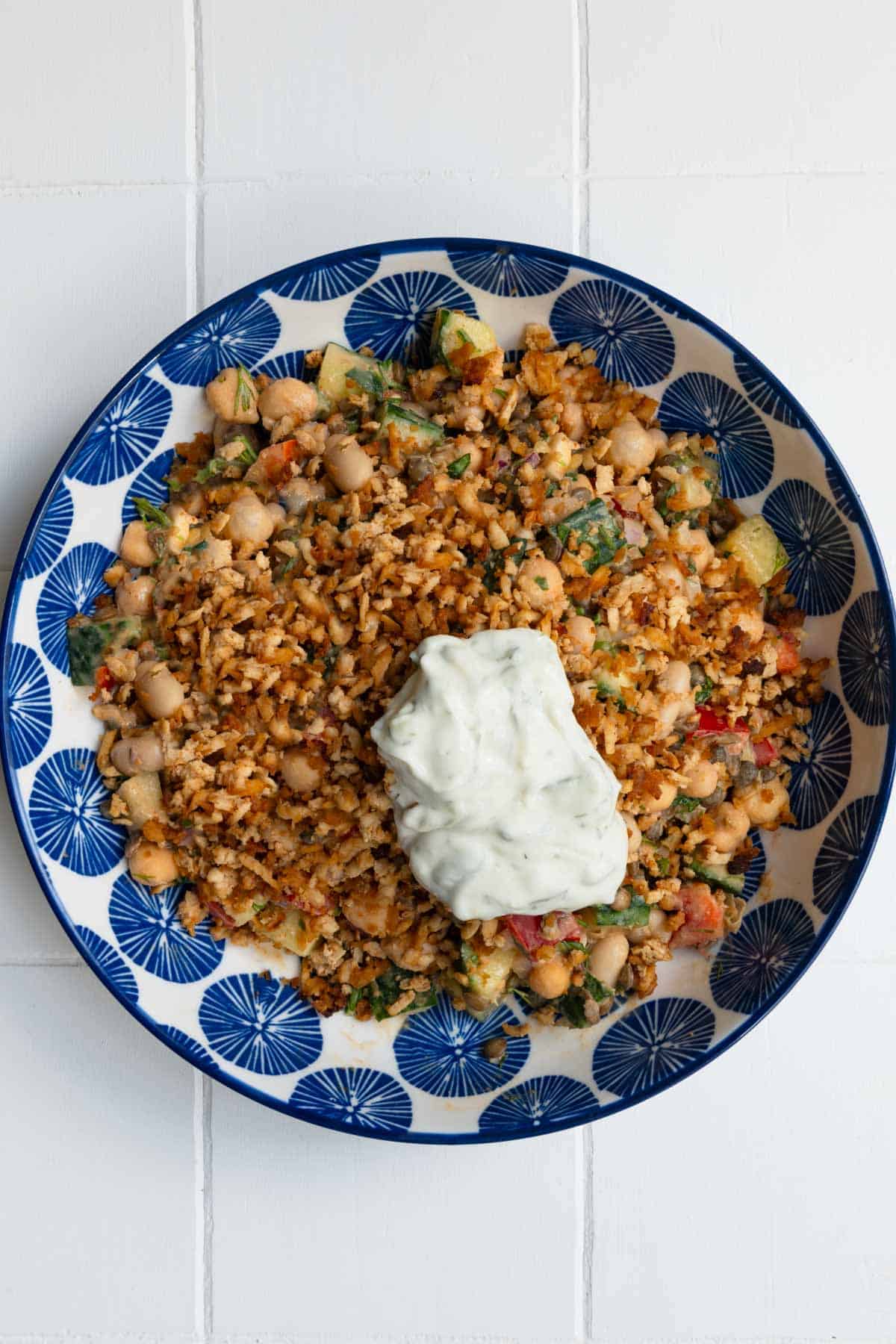 Smoky lemon herb bean salad topped with tofu and vegan tzatziki in a bowl.