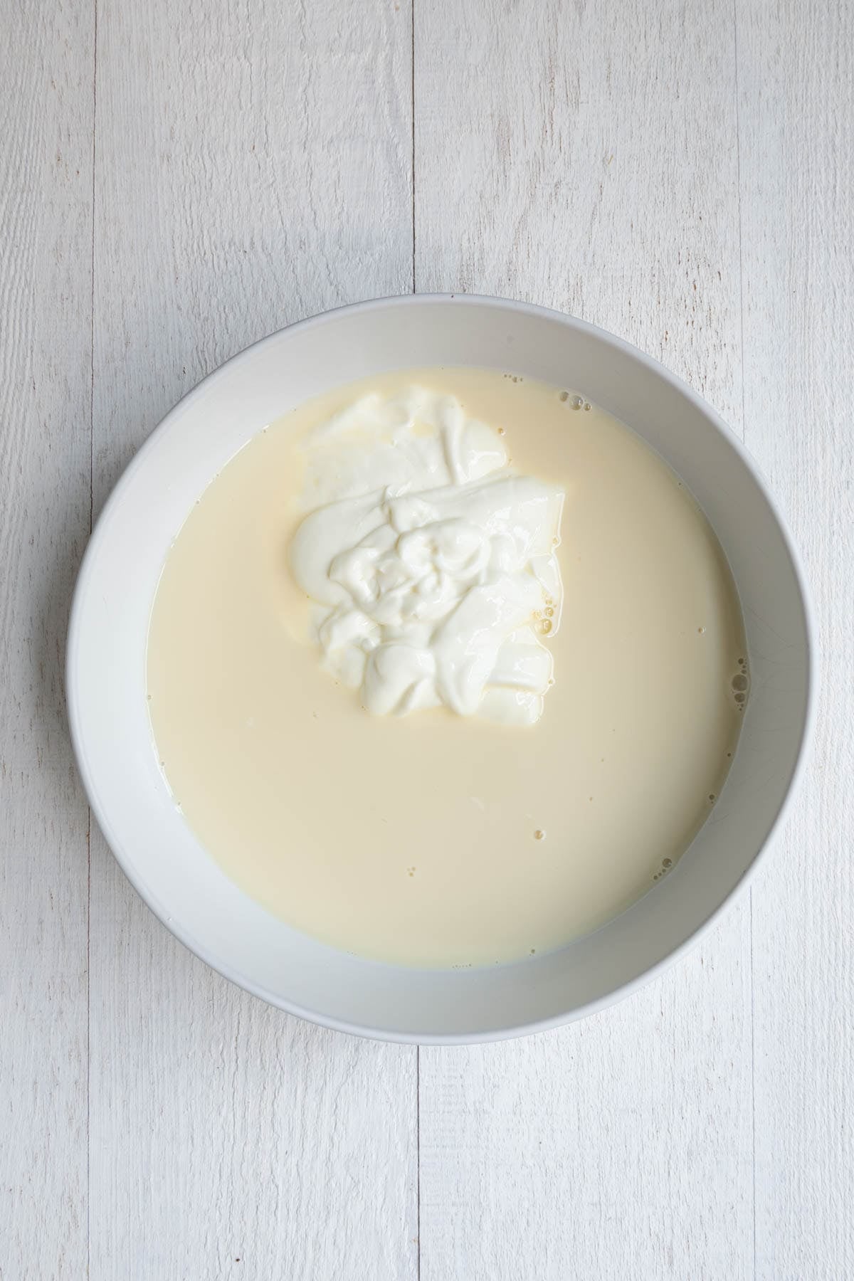 Nondairy milk topped with Greek yogurt in a white bowl.