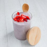 Strawberry chia pudding in a glass jar with a wooden spoon.