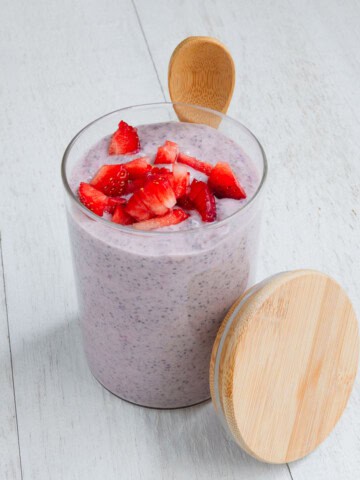 Strawberry chia pudding in a glass jar with a wooden spoon.
