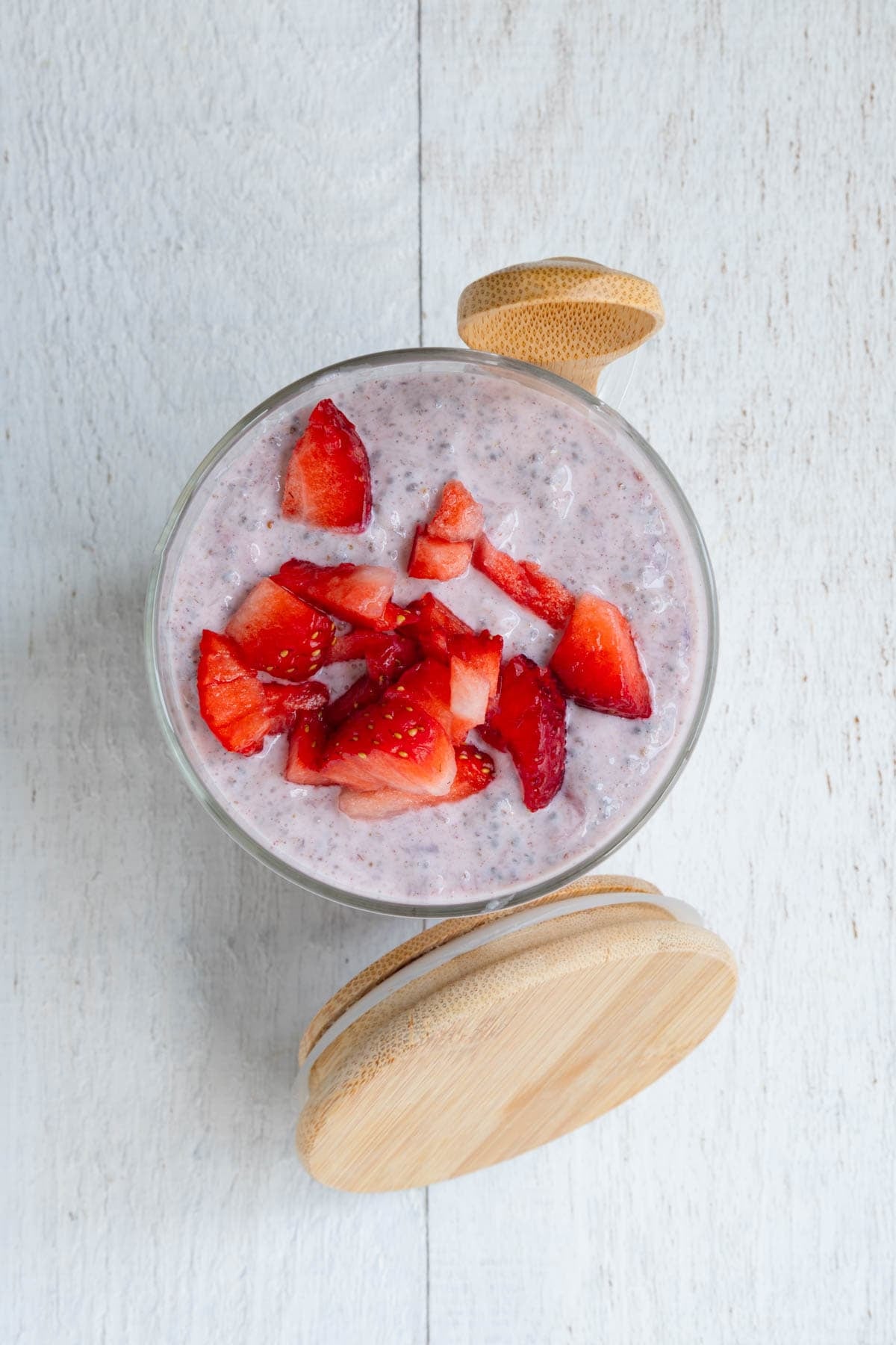 Strawberry chia pudding in a glass jar with a wooden spoon.