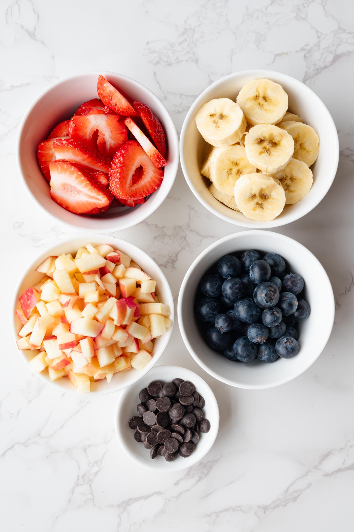Sliced strawberries, banana, chopped apple, blueberries, and dark chocolate chips.