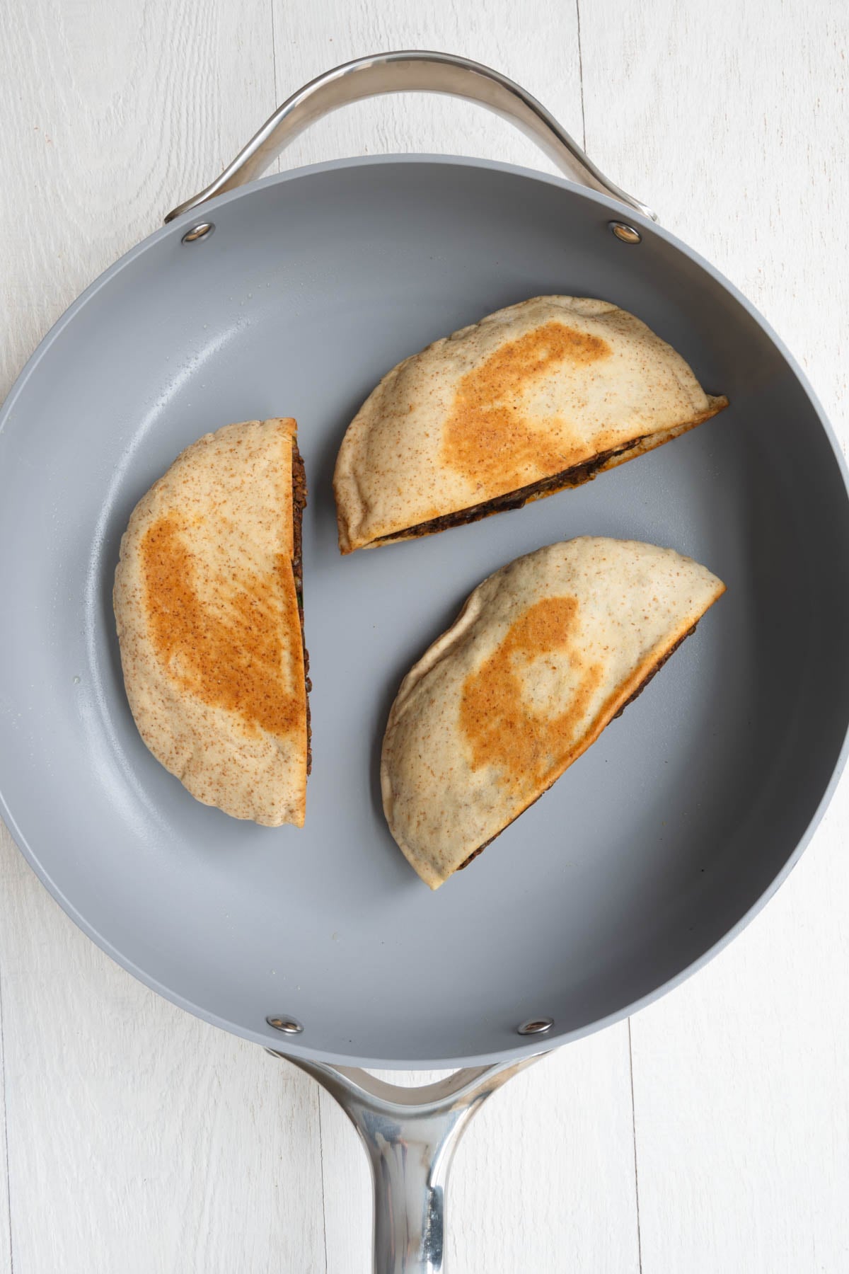 Three lentil-stuffed pitas in a skillet.