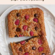 Healthy high-protein banana loaf with yogurt on a white plate sliced in half.