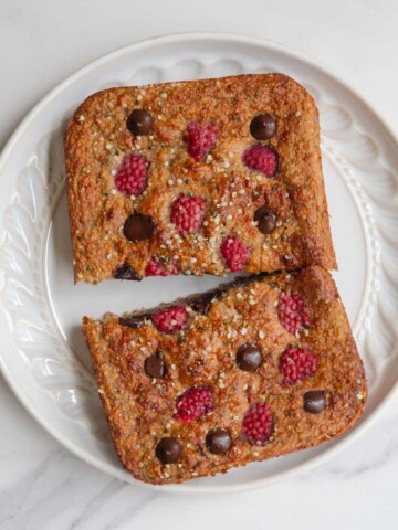 Healthy high-protein banana loaf with yogurt on a white plate sliced in half.