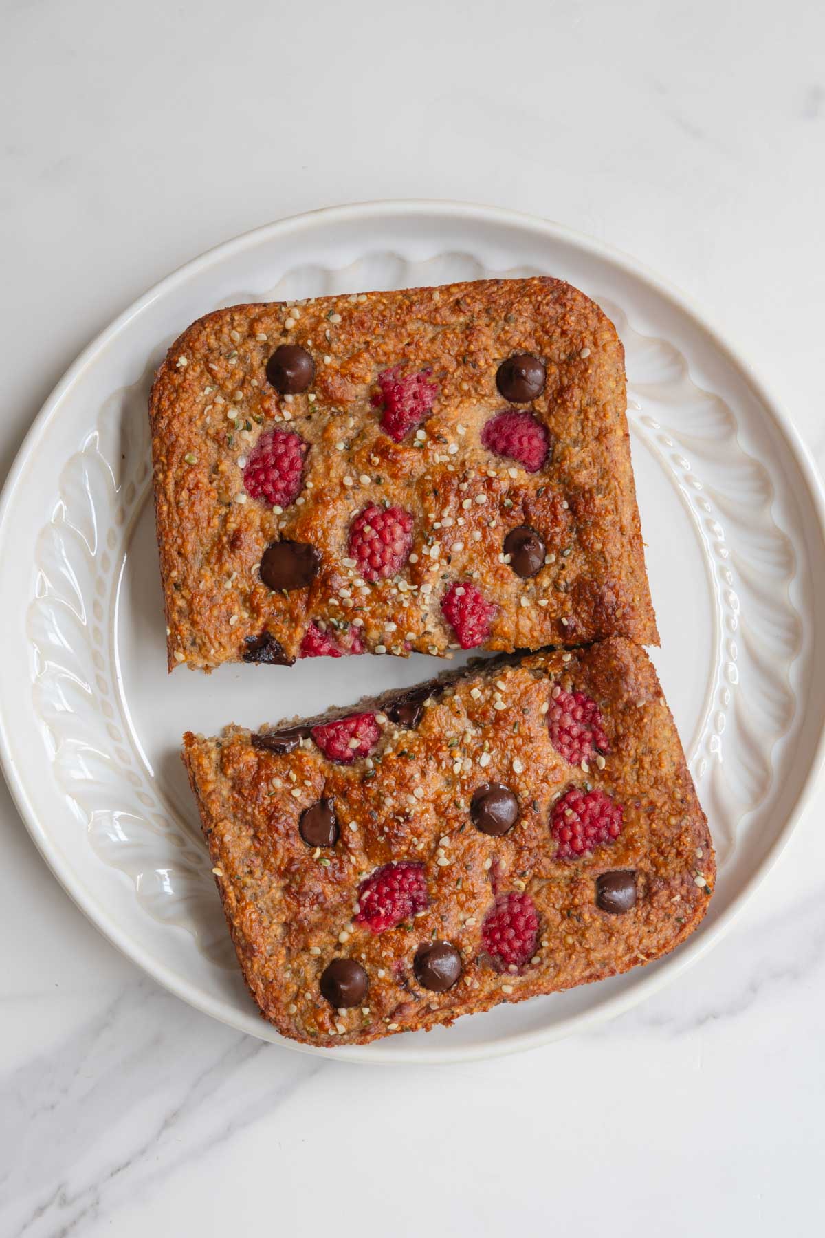 Healthy high-protein banana loaf with yogurt on a white plate sliced in half.