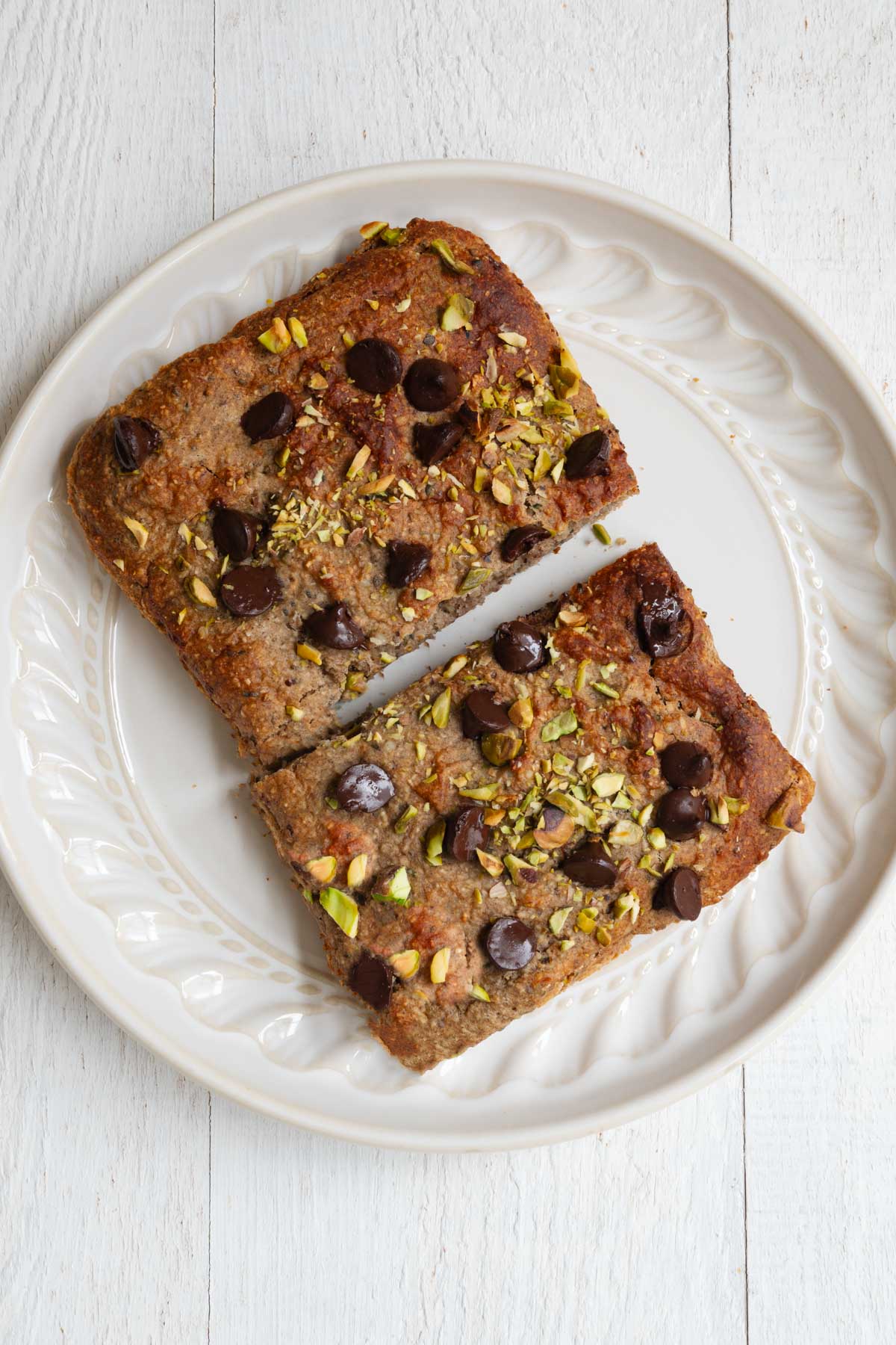 Healthy high-protein banana loaf with yogurt on a white plate sliced in half.