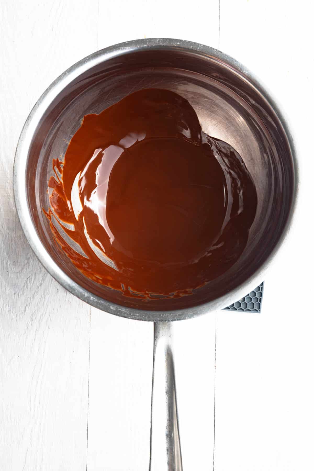 Melted chocolate chips in a metal bowl over a saucepan with hot water.