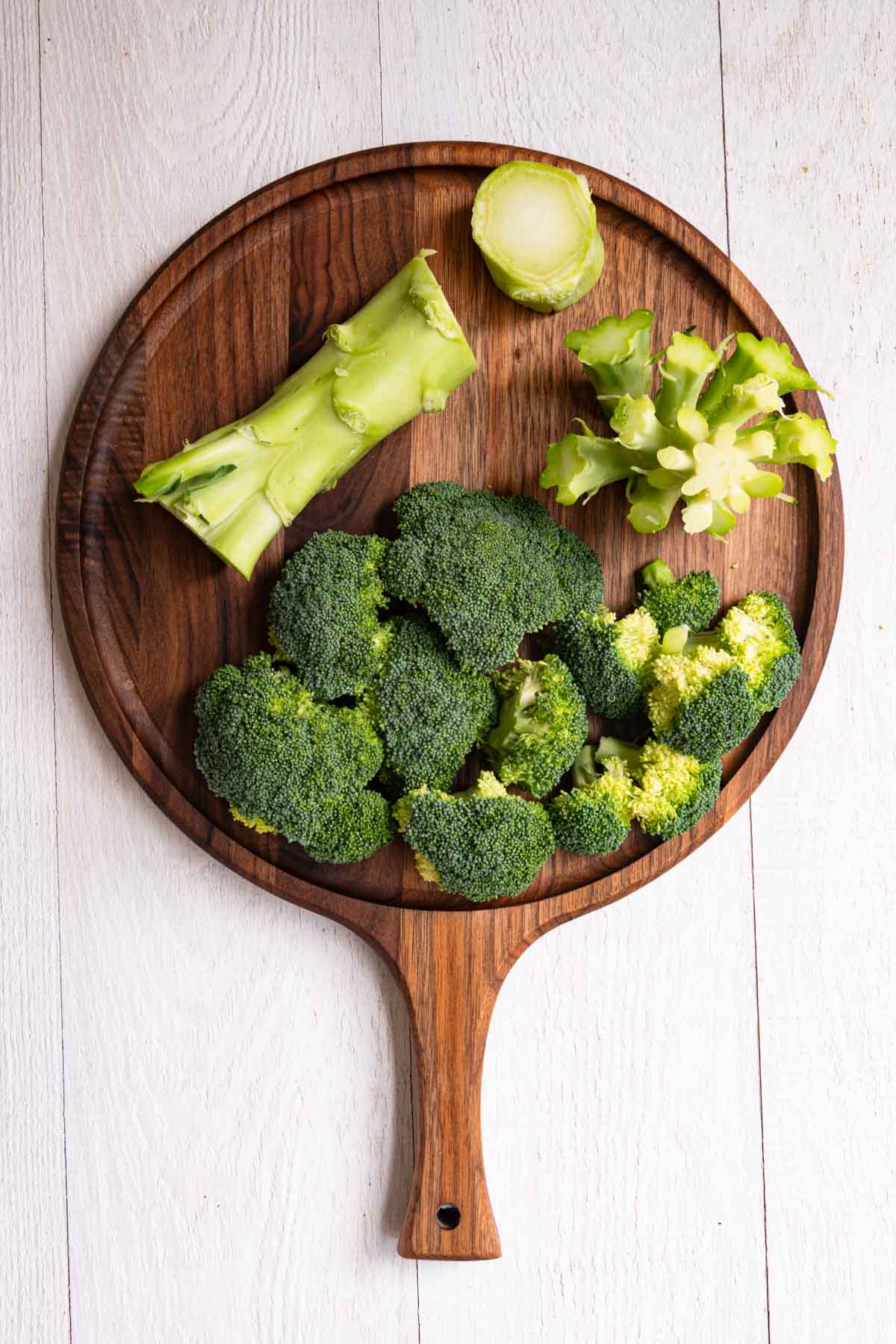 Chopped large broccoli florets and stem on a cutting board.
