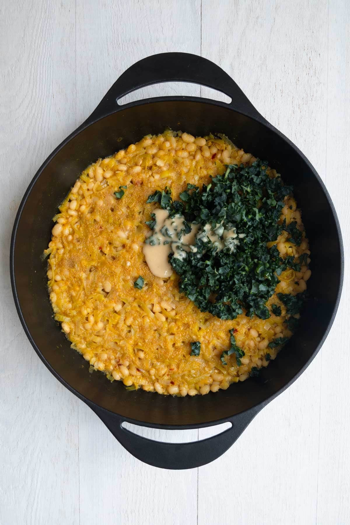 Cooked white beans and amaranth in a large cast-iron skillet with chopped kale, and miso.