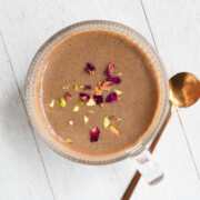 Easy protein chai latte naturally sweetened with dates topped with rose petals and chopped pistachios.