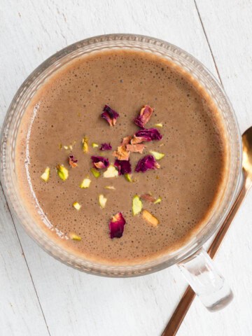 Easy protein chai latte naturally sweetened with dates topped with rose petals and chopped pistachios.