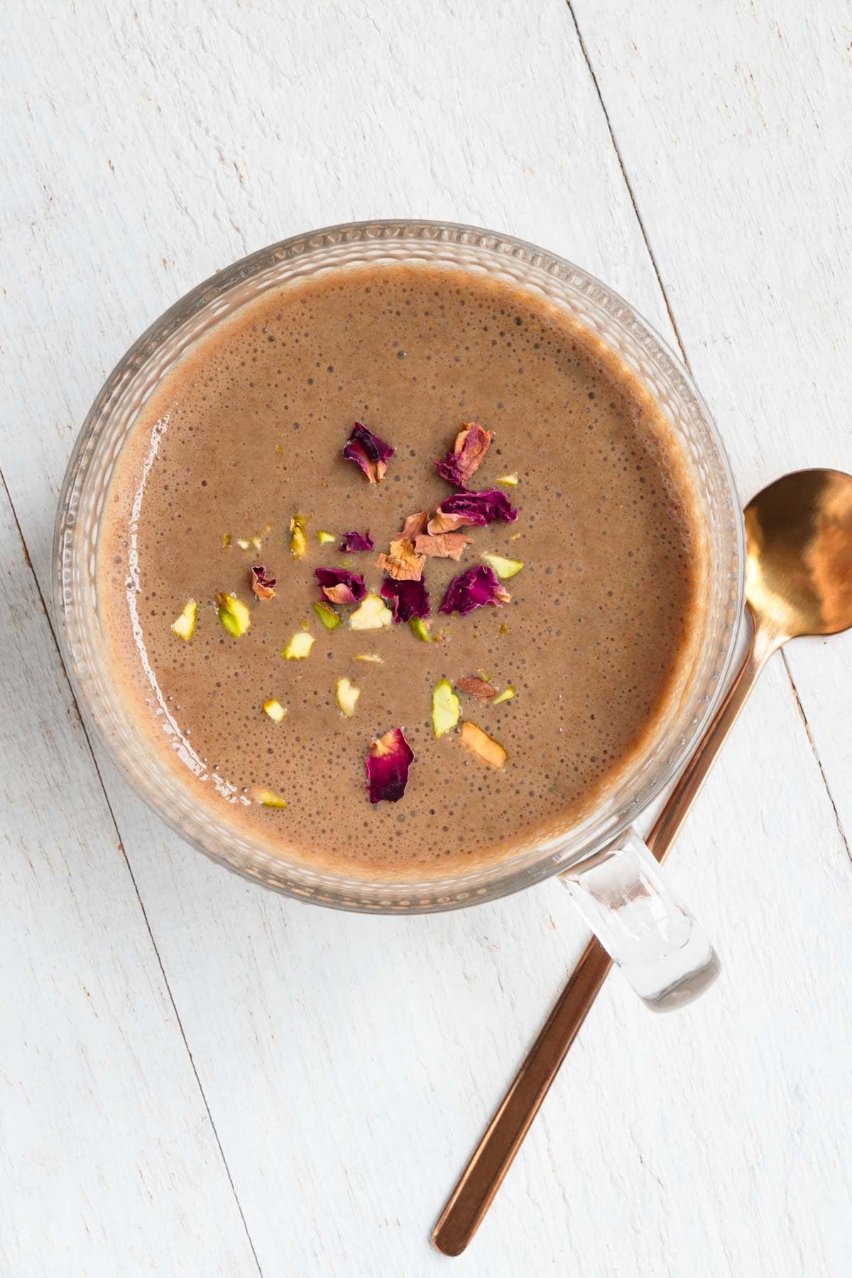 Easy protein chai latte naturally sweetened with dates topped with rose petals and chopped pistachios.