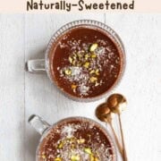 Healthy chocolate pudding topped with pistachios and coconut flakes in two glasses.
