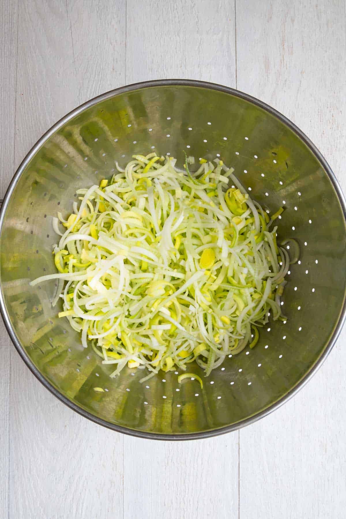 Cut and washed leeks in a large metal strainer.