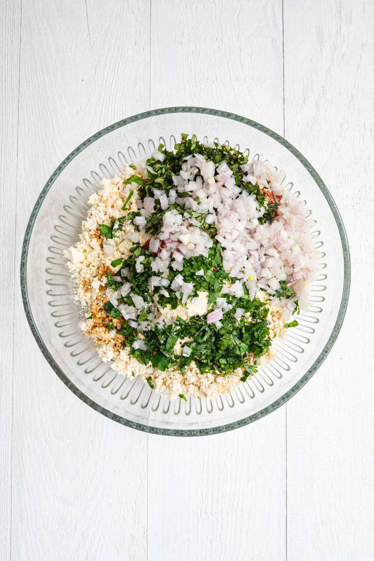 Thai red curry paste, sriracha, tomato paste, red onions, fresh basil, and cilantro in a bowl.