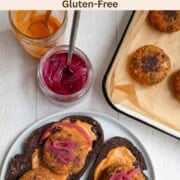 Gluten-free tofu burgers served on pumpernickel toast with orange sauce and pickled red onion and leftovers on a baking sheet.