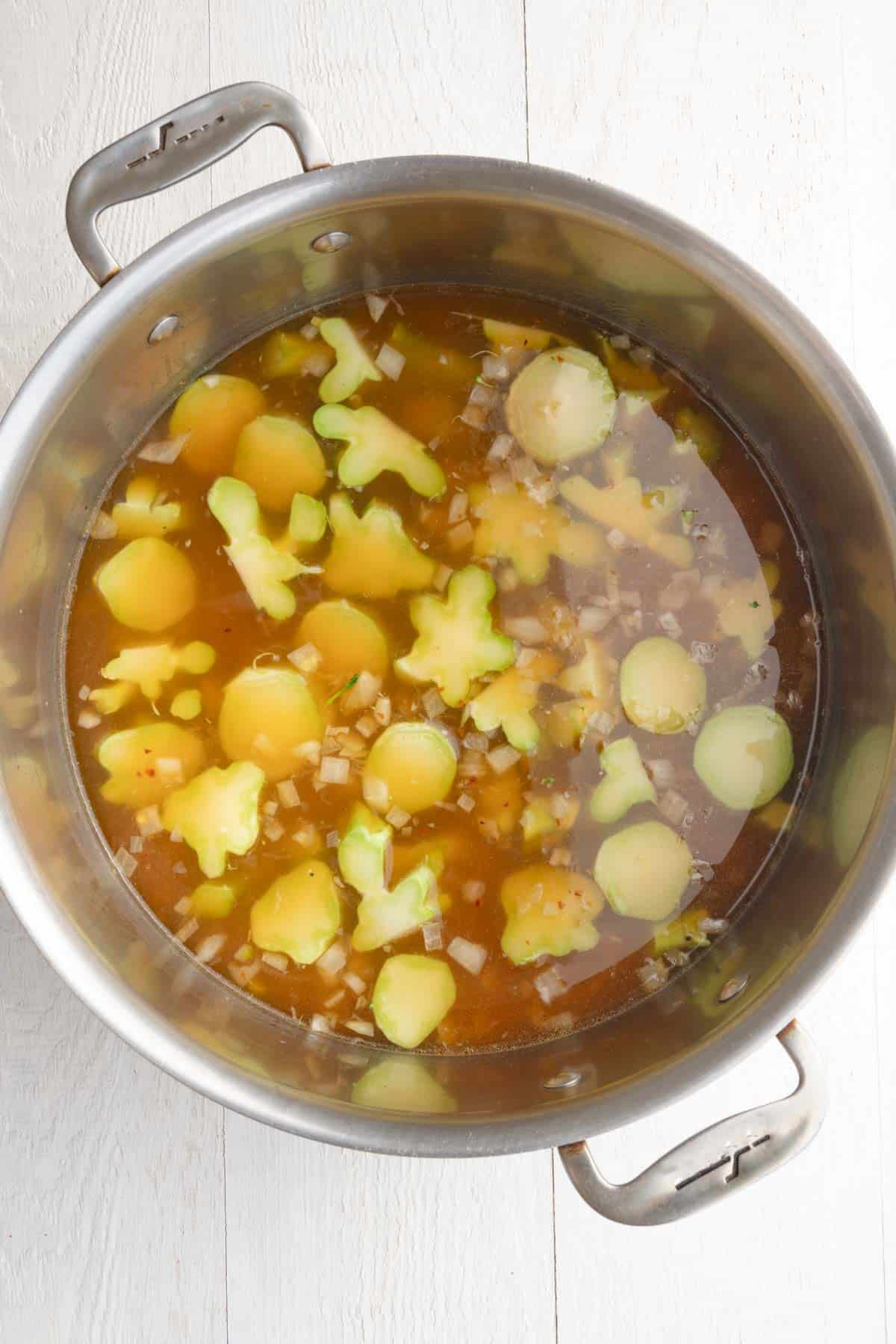 Vegetable broth, sliced broccoli stems, onion, garlic, and seasoning in a large saucepan.