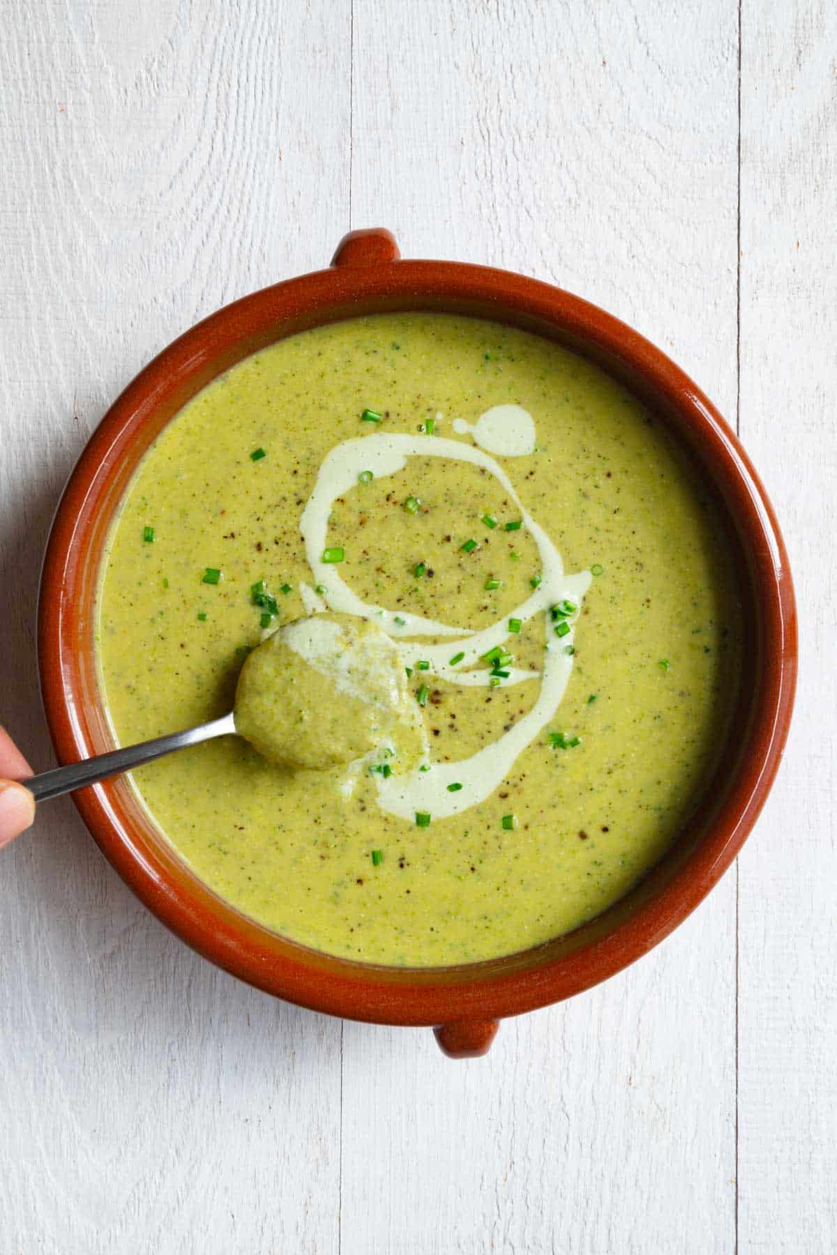 Vegan broccoli soup topped with tofu cream and chopped chives.