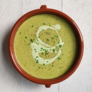Vegan broccoli soup topped with tofu cream and chopped chives.