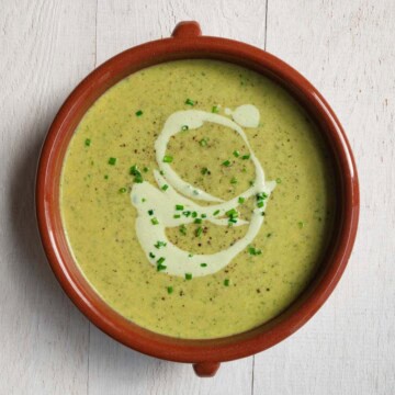 Vegan broccoli soup topped with tofu cream and chopped chives.