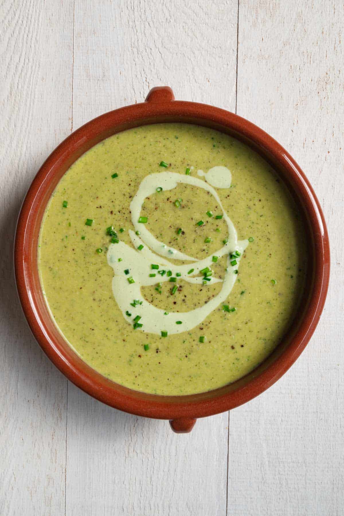 Vegan broccoli soup topped with tofu cream and chopped chives.