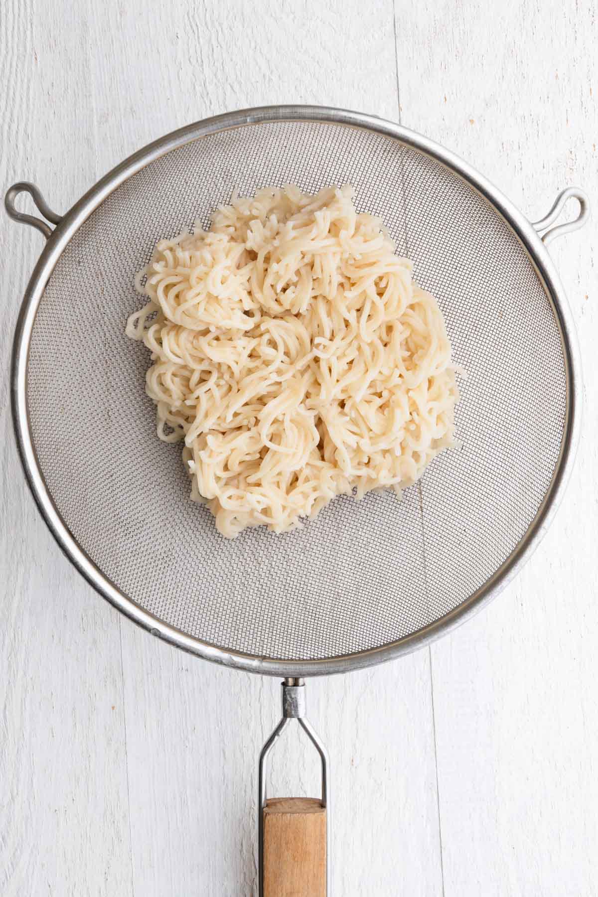 Cooked ramen in a fine mesh sieve.