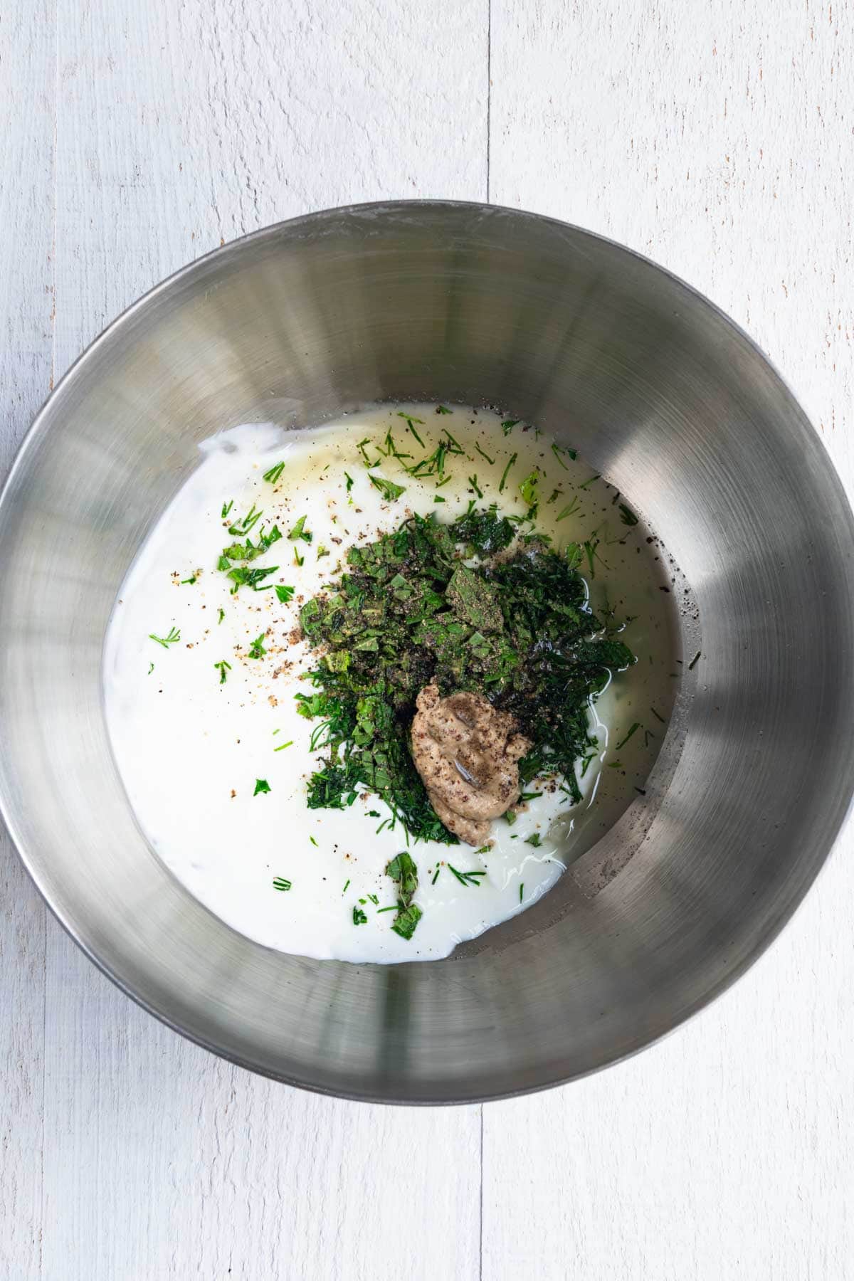 Yogurt, mustard, garlic, lemon juice, mint, and dill in a mixing bowl.