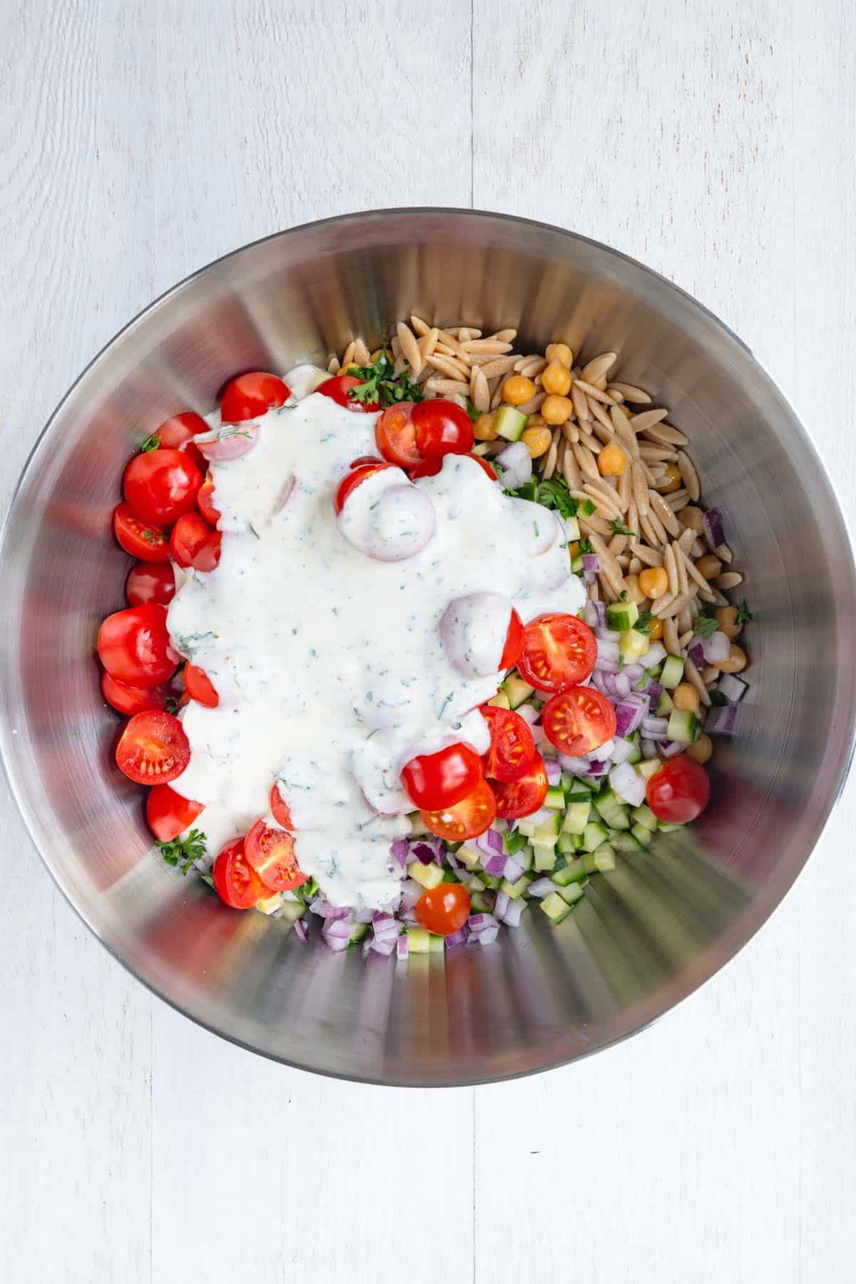 Mint, red onion, cucumber, chickpeas, orzo, tomatoes, and parsley with yogurt dressing.